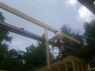 Carpenter setting a ridge beam over a new addition frame — Ice Dam Removal by Roofing Brothers in Brentwood