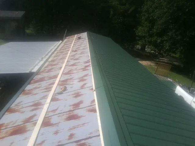 Old rusted panels beside newly installed green metal roofing — Wind Damage Roof Repair by Roofing Brothers in Brentwood