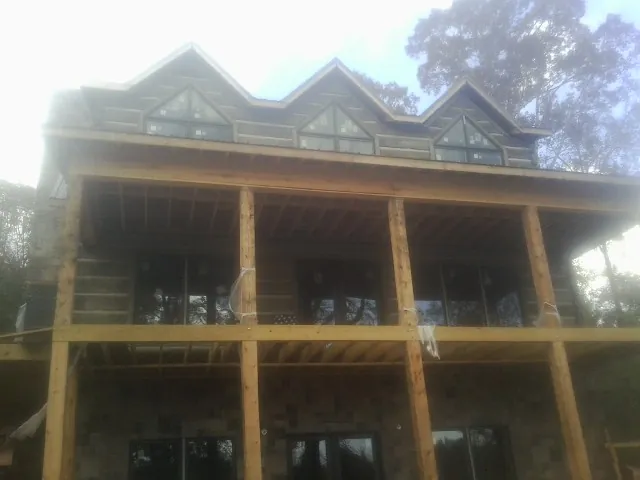 Dormers and porch framing on a large log home under construction — Roof Coating work by our crew in Brentwood