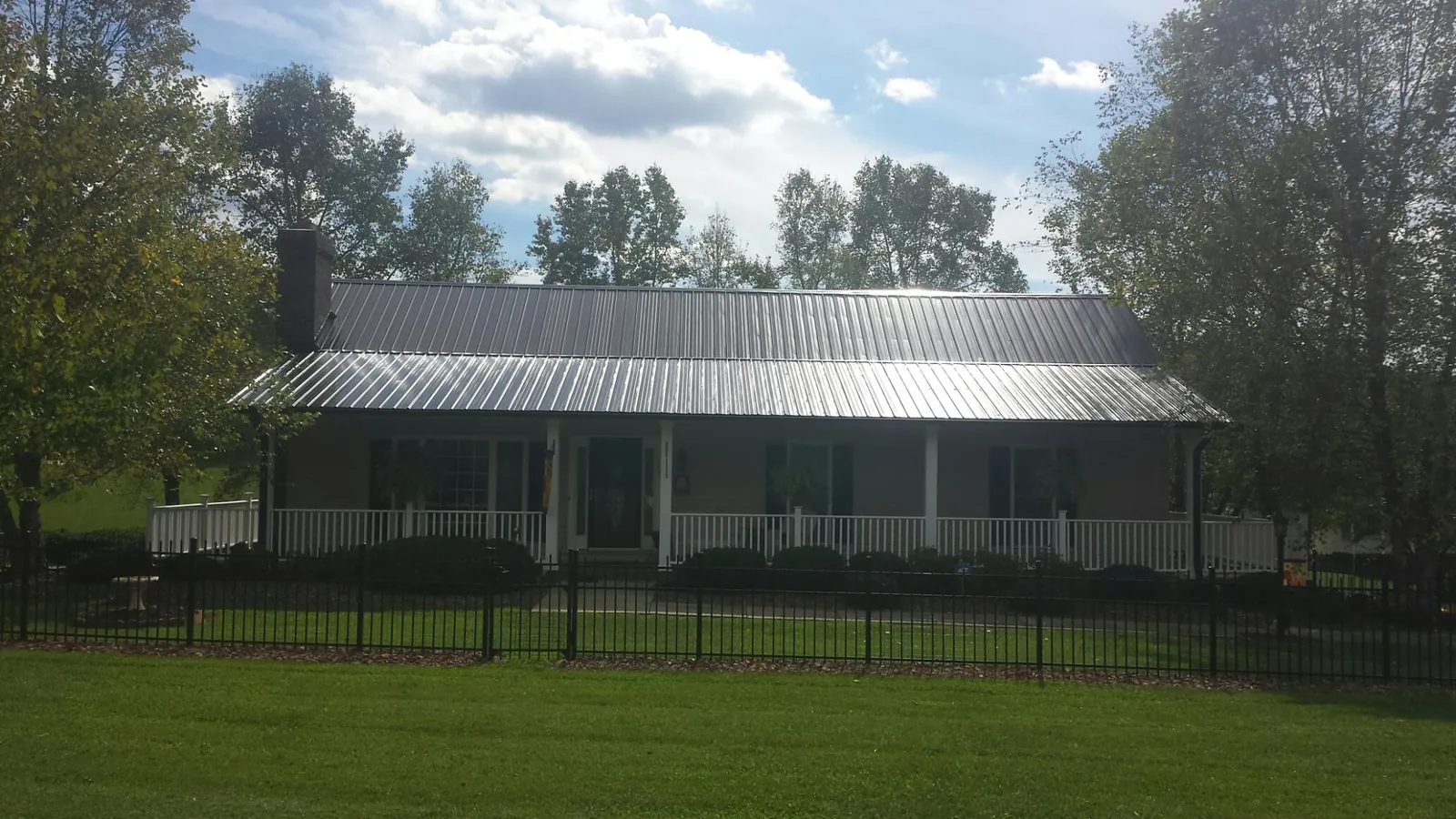 Gray metal roof on a brick ranch with a full width front porch — Gutter Guard Installation work by our crew in Brentwood