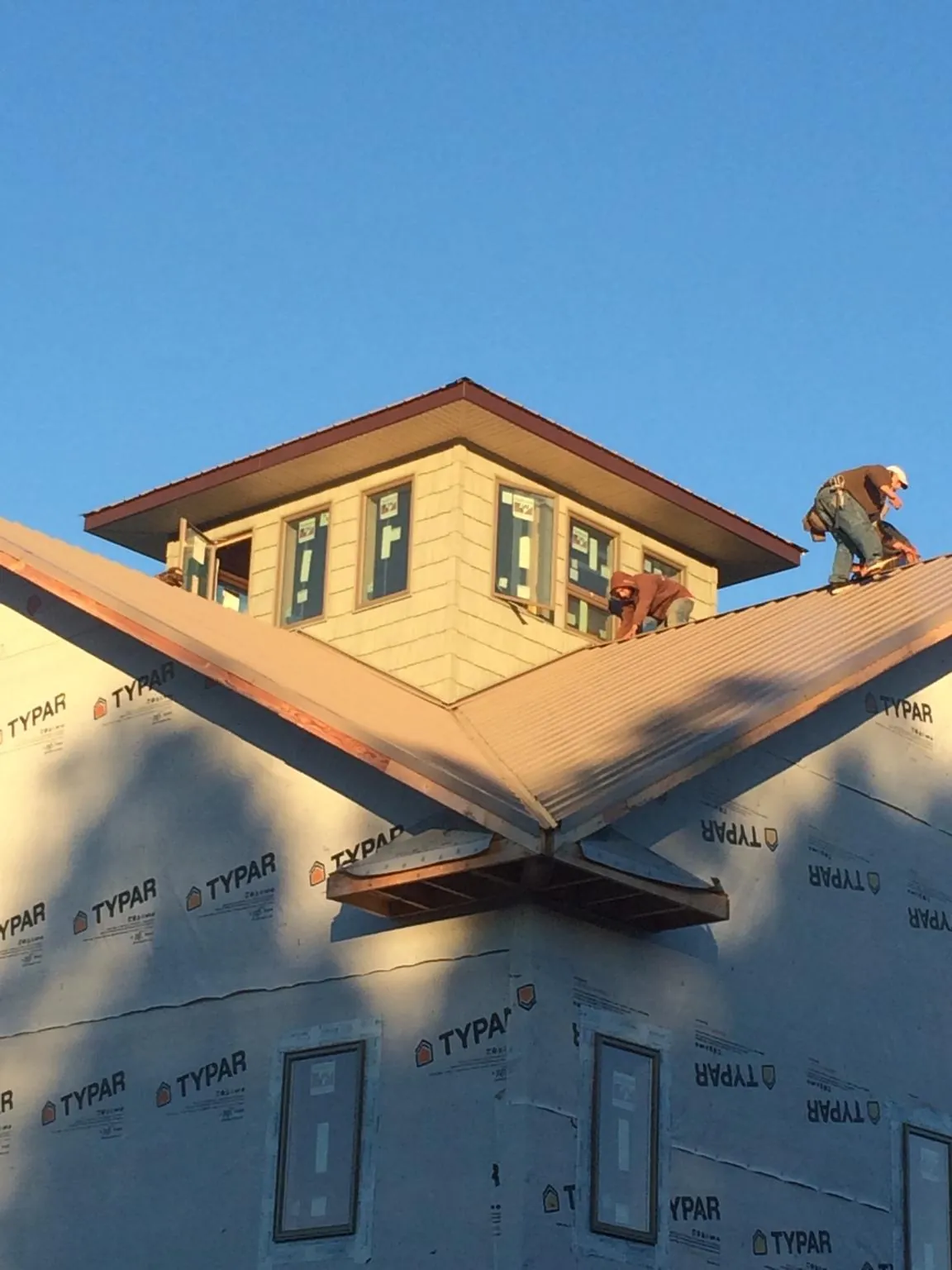 Roofers working around a rooftop cupola on a new metal roof at sunset — Roof Waterproofing in Brentwood by Roofing Brothers